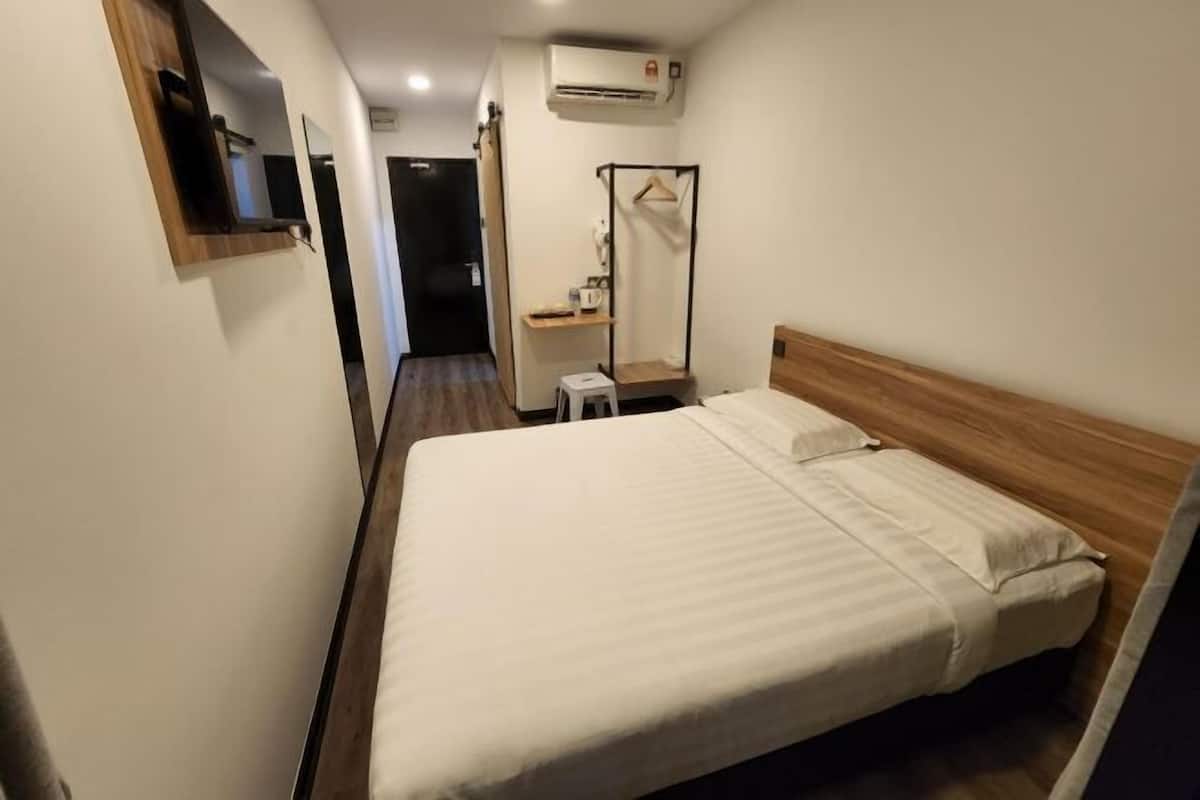 A hotel room with a single bed, a small bedside table, a mirror, and a wardrobe.