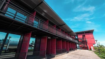 Un edificio moderno con facciata rossa, ampie finestre e una passerella coperta.