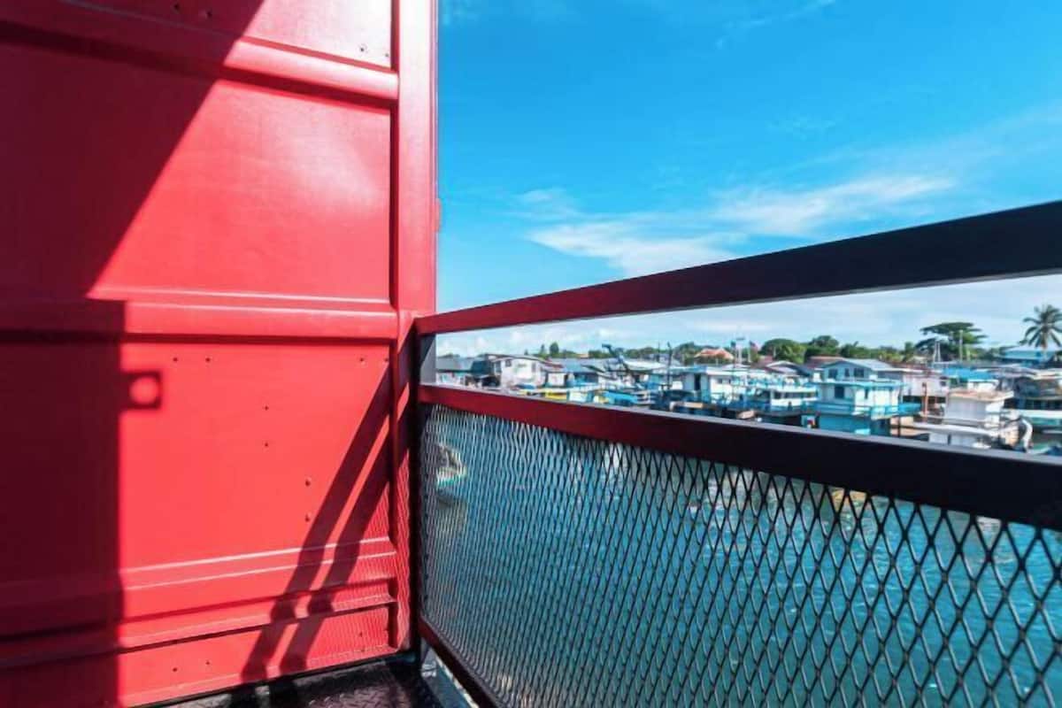 A red structure with a metal railing overlooking a marina with boats.