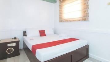 A bedroom with a bed, a nightstand, and a window with blinds.