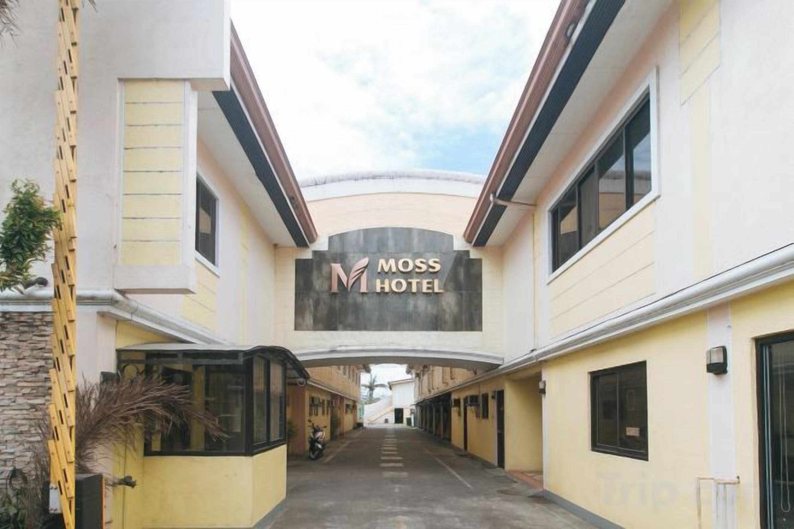 A corridor leading to a hotel entrance with a sign reading 'MOSS HOTEL'.