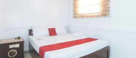 A hotel room with a single bed, a bedside table, and a window with blinds.