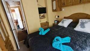 Une chambre d’hôtel avec un lit, des armoires en bois, une télévision et une petite table avec une lampe.