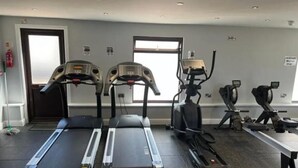Une salle de sport équipée de tapis de course, de vélos elliptiques et d’un vélo d’appartement.