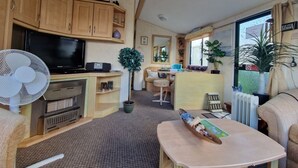 A compact living space with a television, fan, and kitchenette.