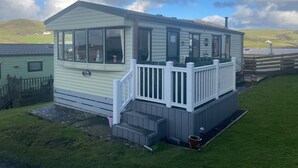 A small, single-story mobile home with a porch and a small set of steps leading up to it.