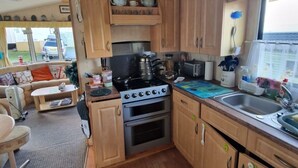 A compact kitchen with wooden cabinets, a stove, and a sink.
