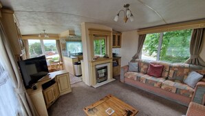 Een gezellig interieur van een camper, met een leefruimte, kitchenette en een televisie.
