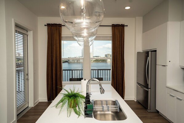 Enjoy a fresh atmosphere in this kitchen with a central island, sink, and plant, offering a view of the city skyline and water.