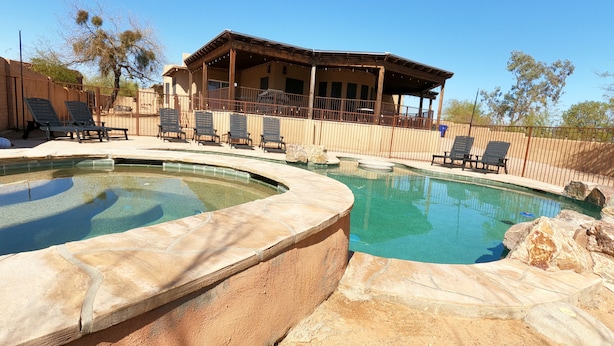 Un área de piscina con sillones de descanso y un porche cubierto.