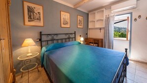 Une chambre à coucher avec un lit, une table de chevet, une lampe et des tableaux encadrés accrochés au mur.