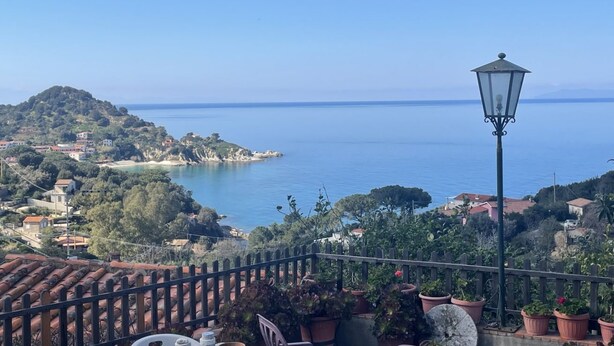 Une vue sur la côte, avec un lampadaire, des plantes en pot et des tuiles en terre cuite sur le toit.