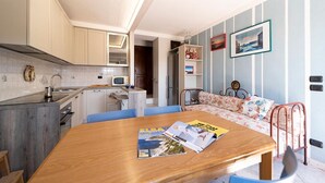 Un espace de vie compact comprenant une cuisine, un coin repas et un petit coin salon avec un canapé et un lit.