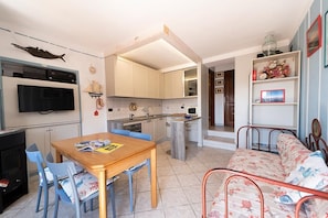 A compact living space with a dining area, kitchenette, and a sofa.