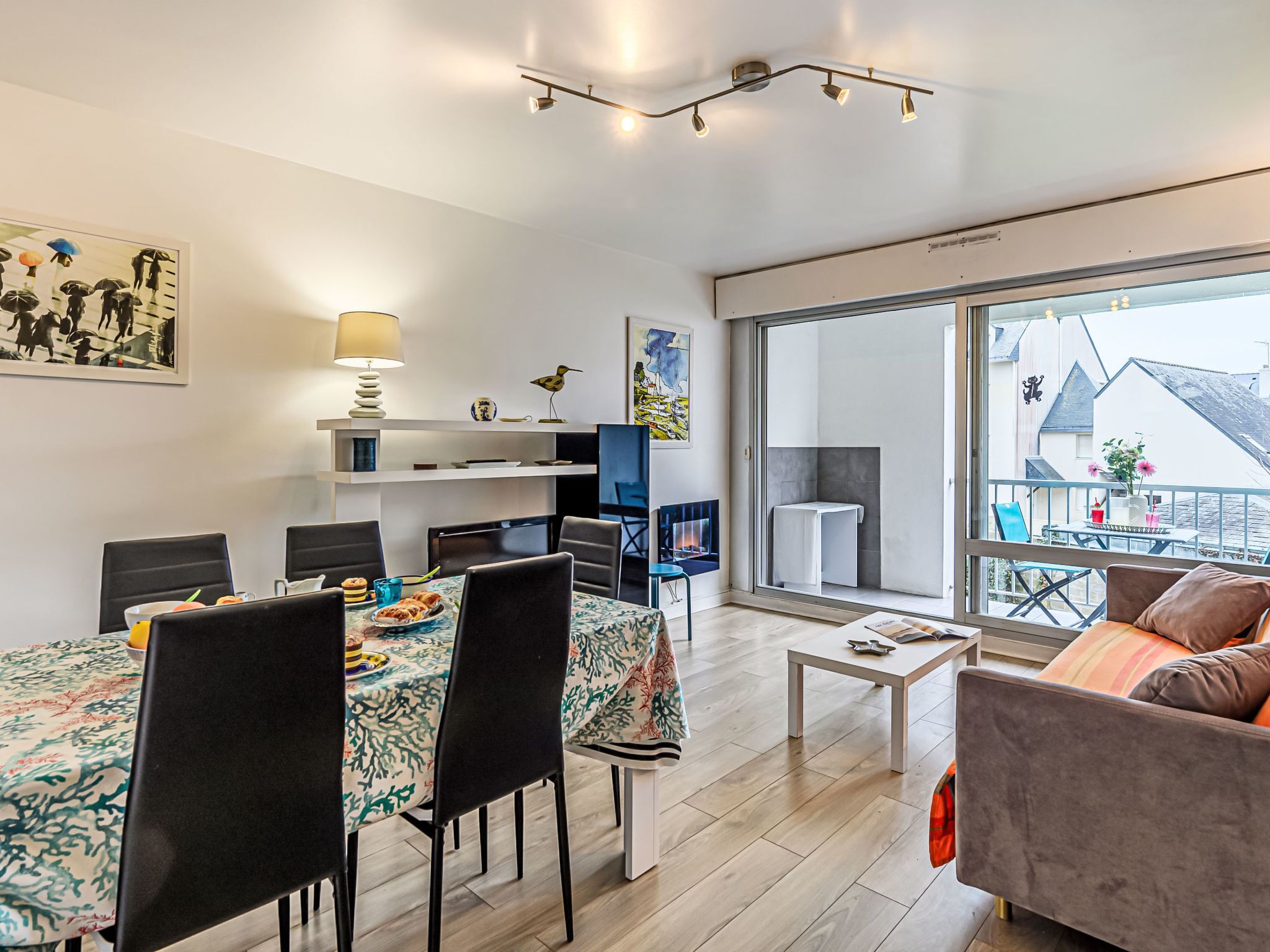 Uma sala de estar moderna com área de jantar, lareira e uma grande porta de vidro deslizante que dá para uma varanda externa.
