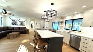 Une cuisine moderne dotée d’un îlot central, de planchers en bois et de luminaires suspendus.