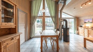 A wooden interior with a dining table, chairs, a TV, and a fireplace. - Ferienhaus mit Sauna im Ferienpark Mirow (Mirow)