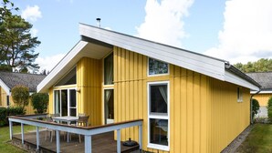 A yellow house with a wooden deck and a white roof. - Ferienhaus mit Sauna im Ferienpark Mirow (Mirow)