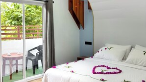 A bedroom with a bed, a ceiling fan, a sliding glass door leading to an outdoor area, and a wooden shelf. - swims maldives (Omadhoo)