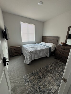 Cozy retreat with a single bed, nightstand, dresser, and TV.