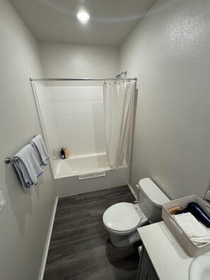Features a white bathtub, toilet, and sink area.