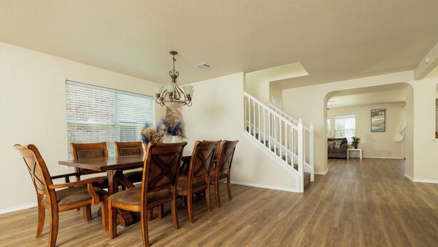 A spacious dining area with a wooden table and chairs, a chandelier, and a staircase leading to another room. - This home is minutes away from:
SEA WORLD
FIESTA TEXAS
RIVERWALK
4 JOINT BASES + (San Antonio)
