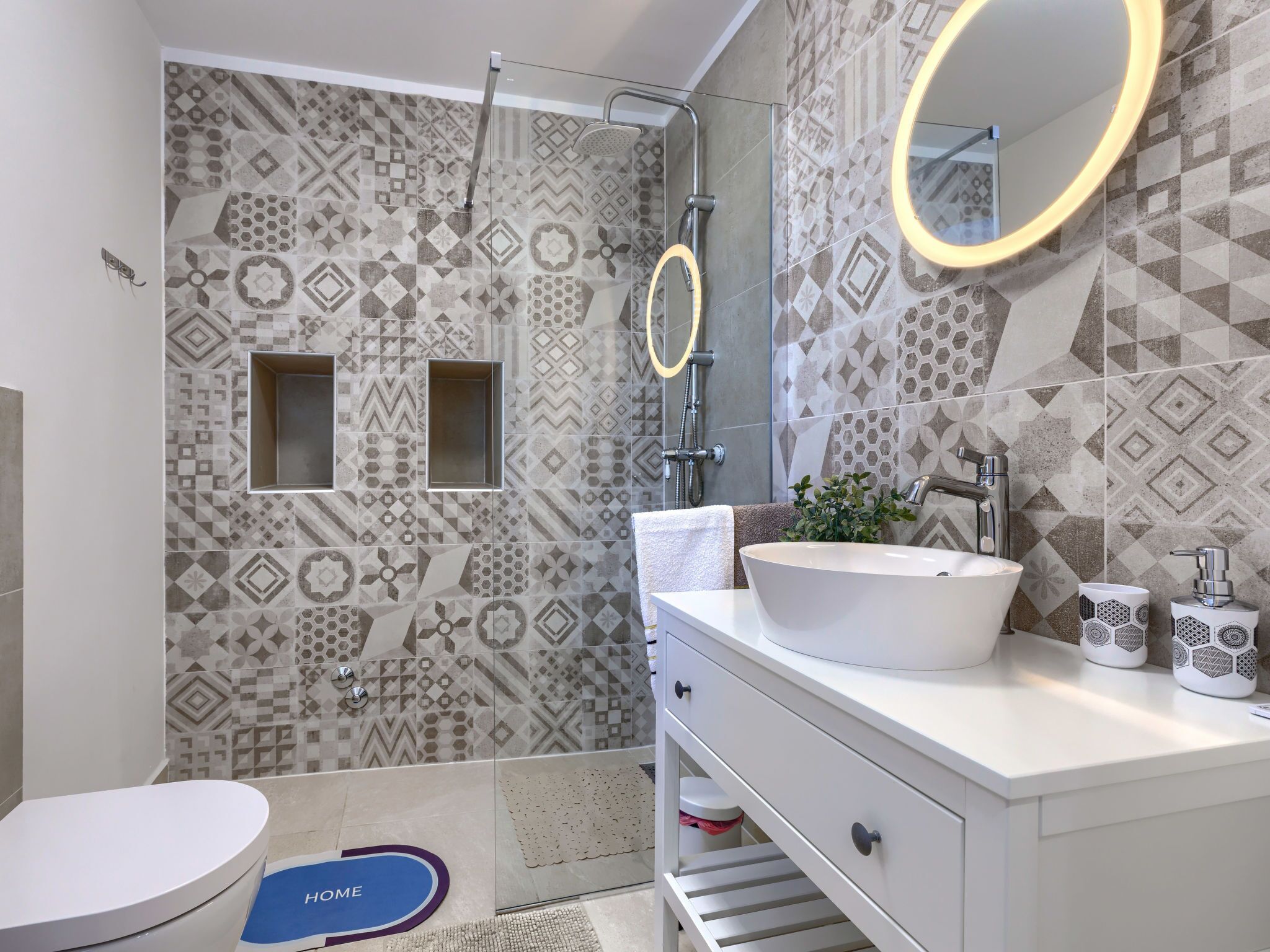 A modern bathroom with patterned tiles, a freestanding bathtub, a vanity with a sink, and a mirror.