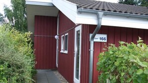 Un bâtiment rouge avec une porte blanche, une fenêtre et une enseigne portant le numéro 166.