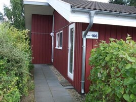 A red building with a white door, a window, and a sign with the number 166.