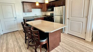 Una cocina moderna con una isla central, sillas de madera y electrodomésticos de acero inoxidable.