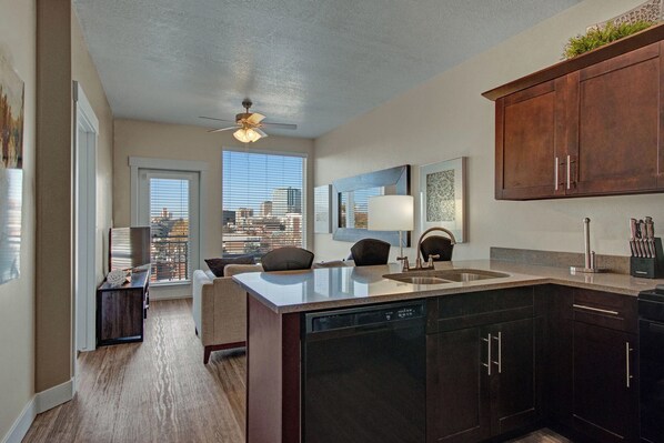 A modern kitchen with a central island, dark cabinetry, and a city view through the windows.