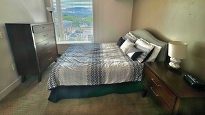 Un dormitorio con cama, cómoda, lámpara y ventana con persianas.