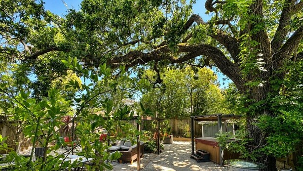 A covered outdoor seating area with a pergola, a hot tub, and a wooden deck.