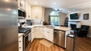 A modern kitchen with white cabinets, stainless steel appliances, a built-in oven, and a dishwasher.