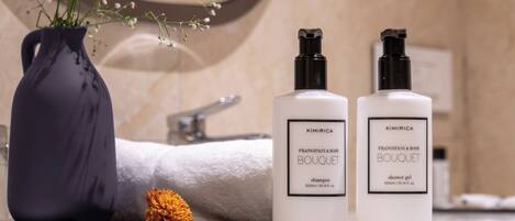 A bathroom vanity with a vase of flowers, two bottles of shampoo, and a towel.