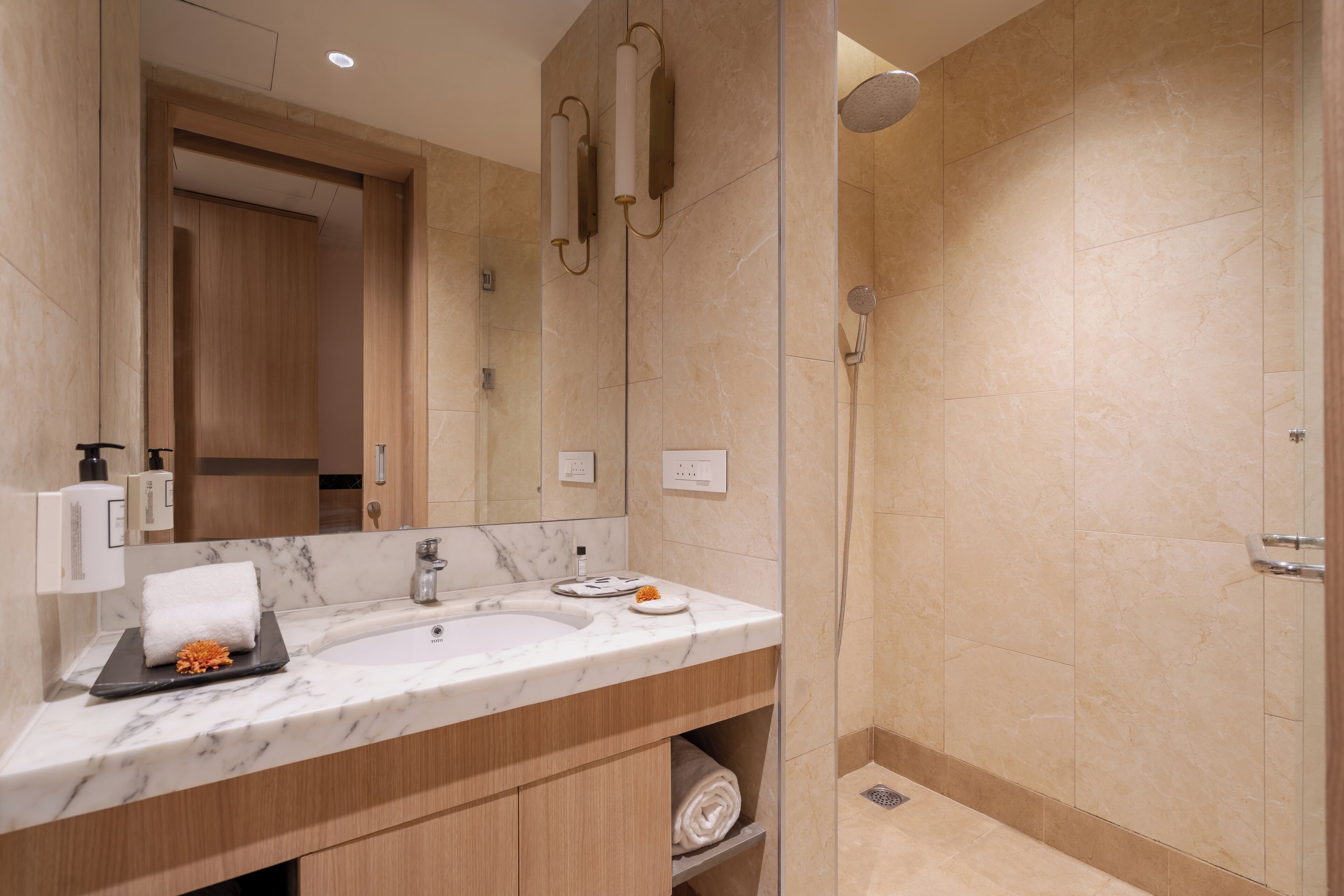 Une salle de bain moderne avec un lavabo en marbre, des meubles en bois, une douche en verre et un grand miroir.