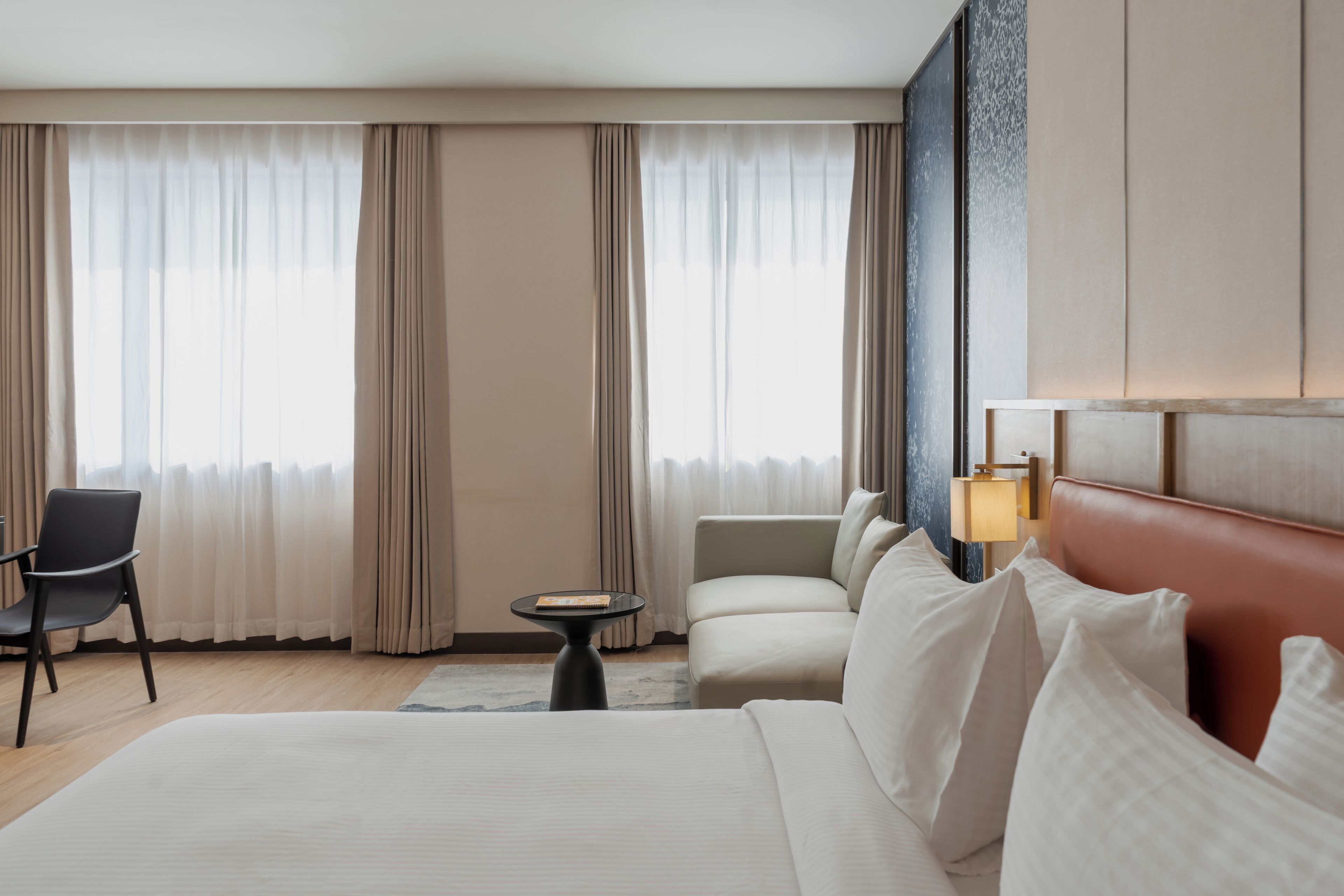 A hotel room with a large bed, a sofa, a chair, and a small table.