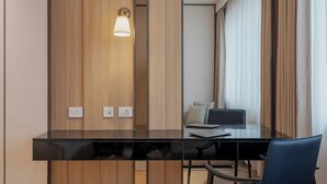 A modern office space with a black desk, two chairs, a lamp, and a laptop. - The Magnus Hotel (Coimbatore)