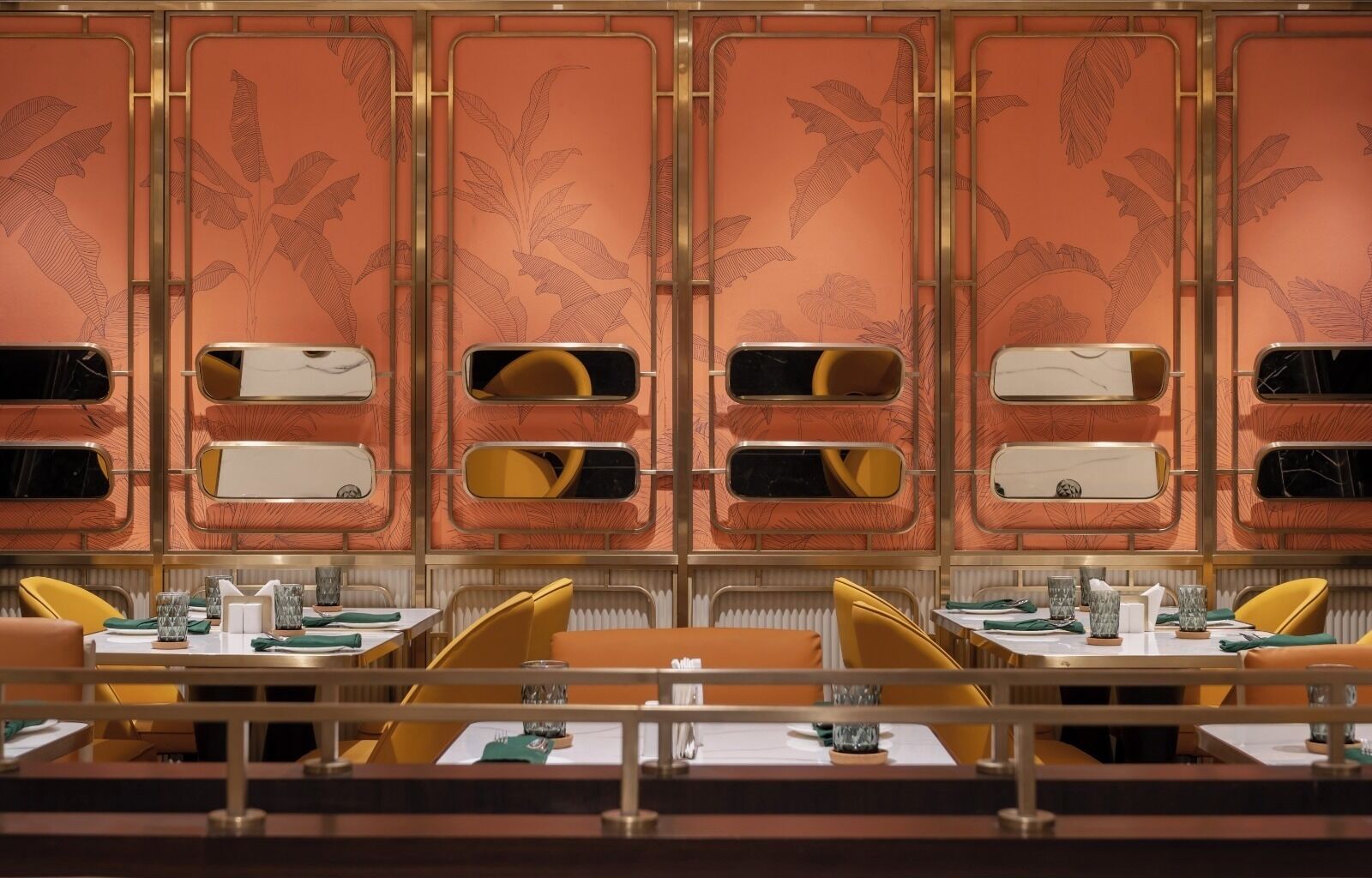 Un restaurant amb un disseny retro, amb cadires grogues i un mur amb un disseny ornamental.