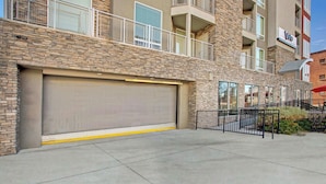 A multi-story building with a stone facade, a large garage door, and a fenced outdoor area. - Luxury Condo in the Best Part of Downtown (Salt Lake City)