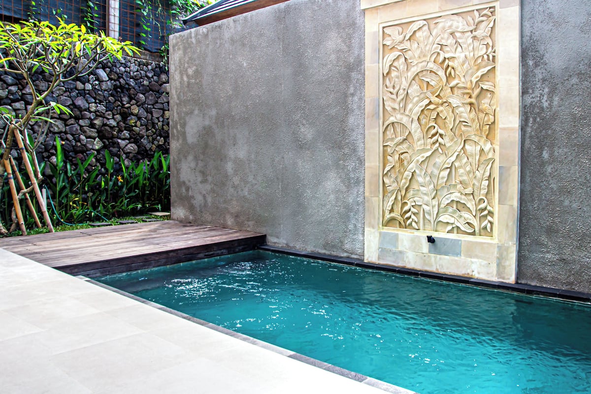 A swimming pool with a stone wall and a decorative panel.