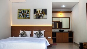Une chambre d’hôtel moderne avec un grand lit, une tête de lit en bois et deux tableaux abstraits accrochés au mur.