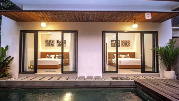 Un hôtel moderne doté de deux chambres, chacune avec une grande fenêtre, un plafond en bois et un petit espace piscine.