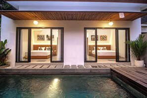 A modern hotel with two bedrooms, each with a large window, a wooden ceiling, and a small pool area. - Varila Villa Ubud (Mas)