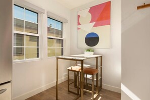 Simple, functional space with a single window, small table, and two stools.