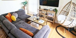 A living room with a sofa, coffee table, and a hanging chair.
