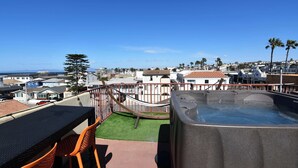 A rooftop terrace with a hot tub, outdoor seating, and a view of the ocean and residential buildings. - Seaside Sanctuary - Rooftop Deck & Hot Tub (Hermosa Beach)