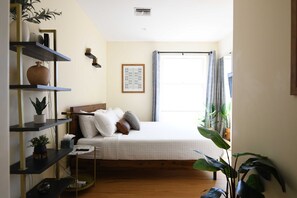 A bedroom with a bed, shelves, and a window.
