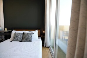 A hotel room with a bed, a desk, and a view of the outside. - Seaside Sanctuary - Rooftop Deck & Hot Tub (Hermosa Beach)