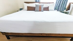 A neatly made bed with white linens and several pillows, including striped and solid brown ones. - Seaside Sanctuary - Rooftop Deck & Hot Tub (Hermosa Beach)